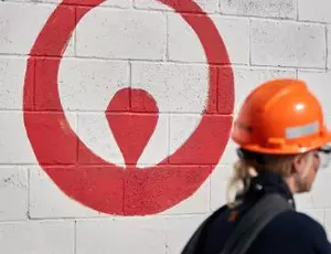 A Veolia employee wearing a backpack walks by an exterior wall with the Veolia logo painted on it