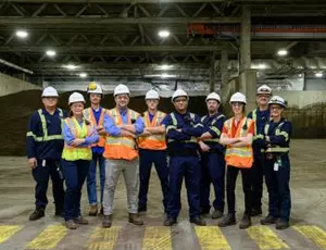 A group of Veolia employees stands in a facility smiling at the camera