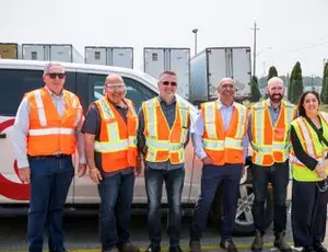 A group of Veolia employees stands in a facility smiling at the camera