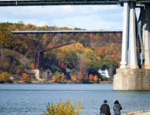 Two people walking in a park by a river