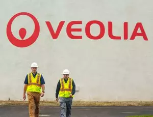 Two Veolia employees walk by a large tank with a Veolia logo on it