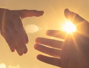 Two hands reaching to help one another