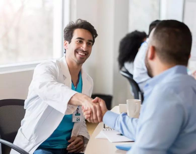 A doctor shakes hands with a patient