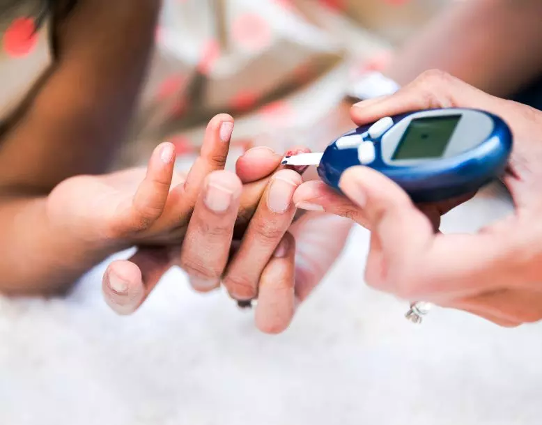 A diabetes blood sugar monitor being used on a person's finger