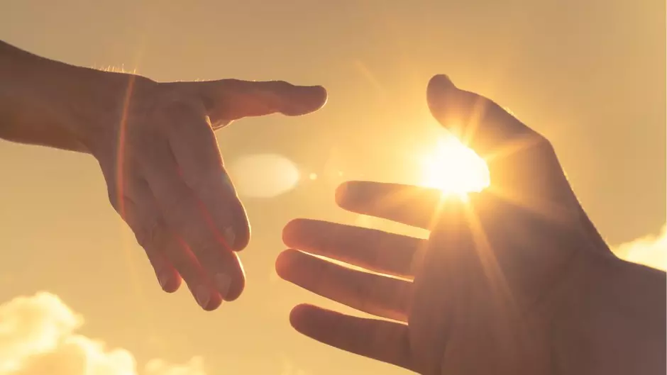 Two hands reaching to help one another