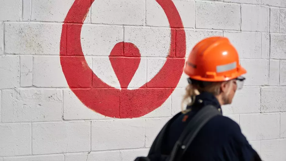 A Veolia employee wearing a backpack walks by an exterior wall with the Veolia logo painted on it