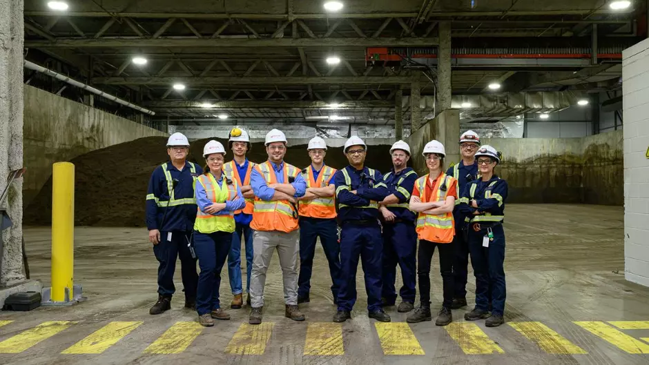 A group of Veolia employees stands in a facility smiling at the camera