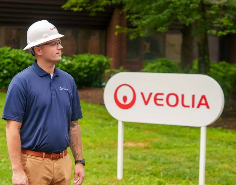 A Veolia employee stands by a Veolia sign