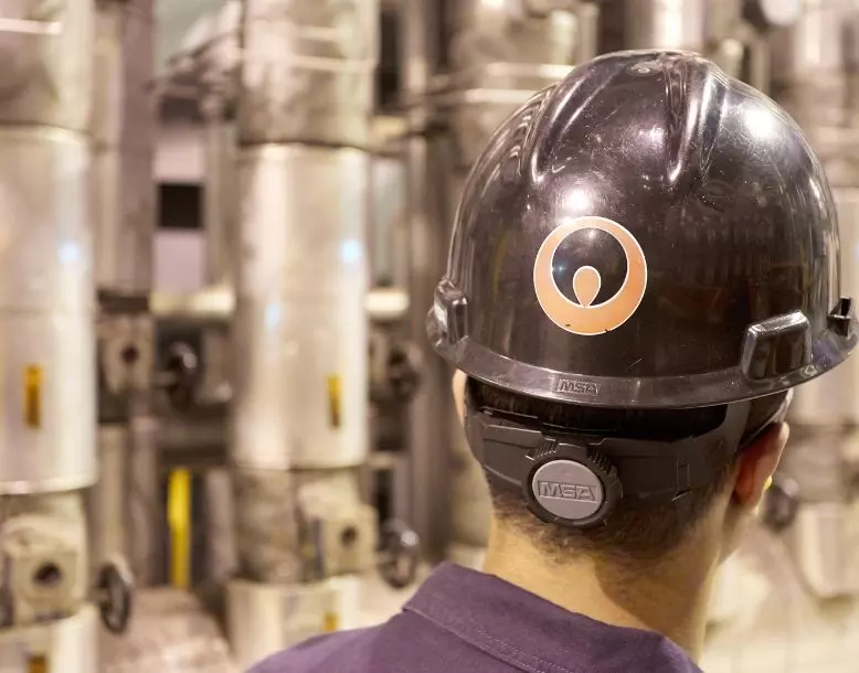 The back of a Veolia employee's hardhat is seen as he looks into a facility