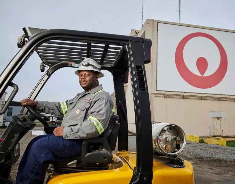 A Veolia employee operates a forklift with a Veolia logo in the background