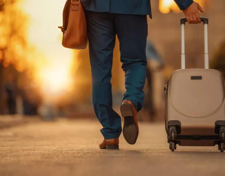 A person walks with a rolling suitcase