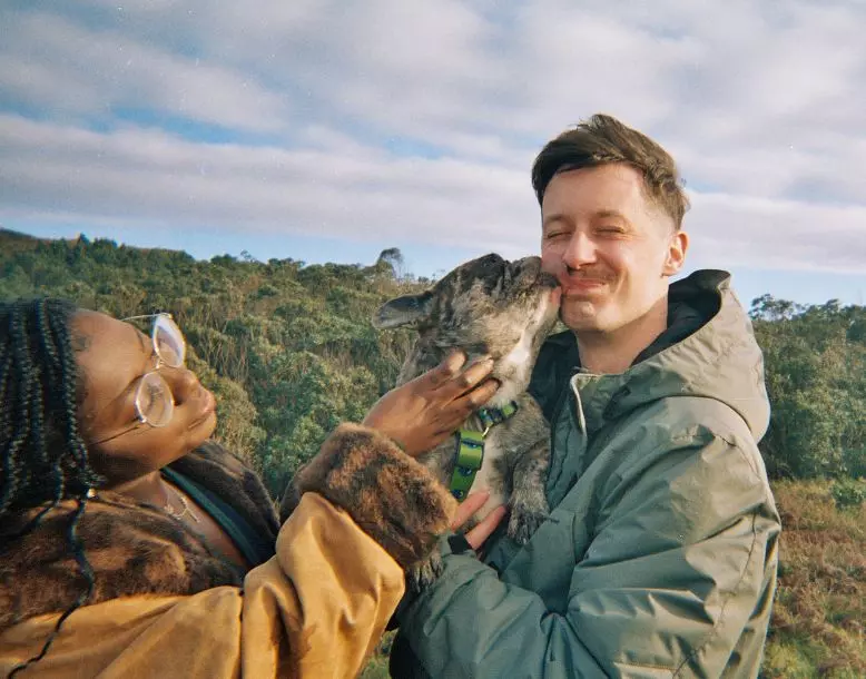 Two people smile while holding their pet dog